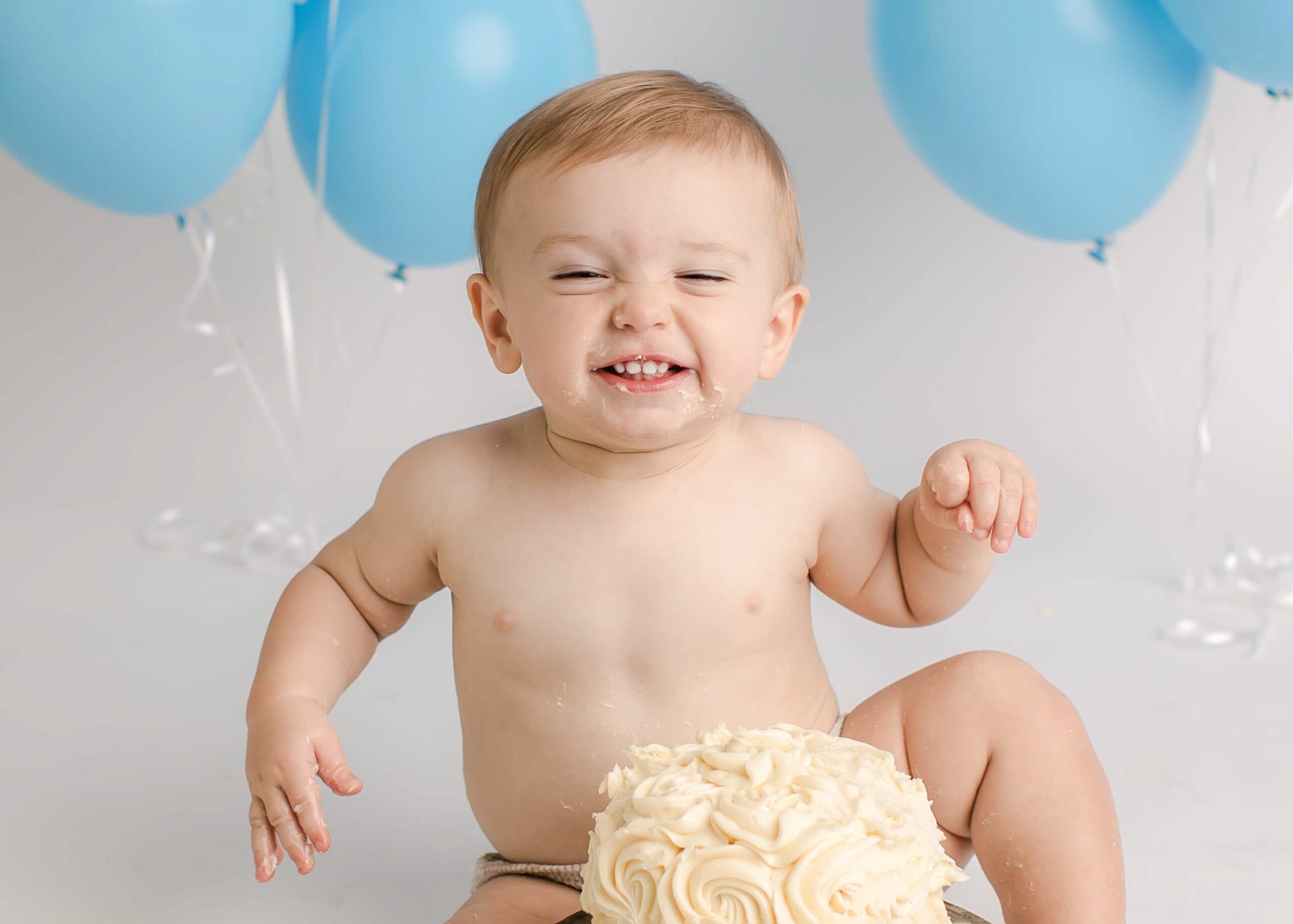 a milestone baby boy cake smash photograph with blue baloons